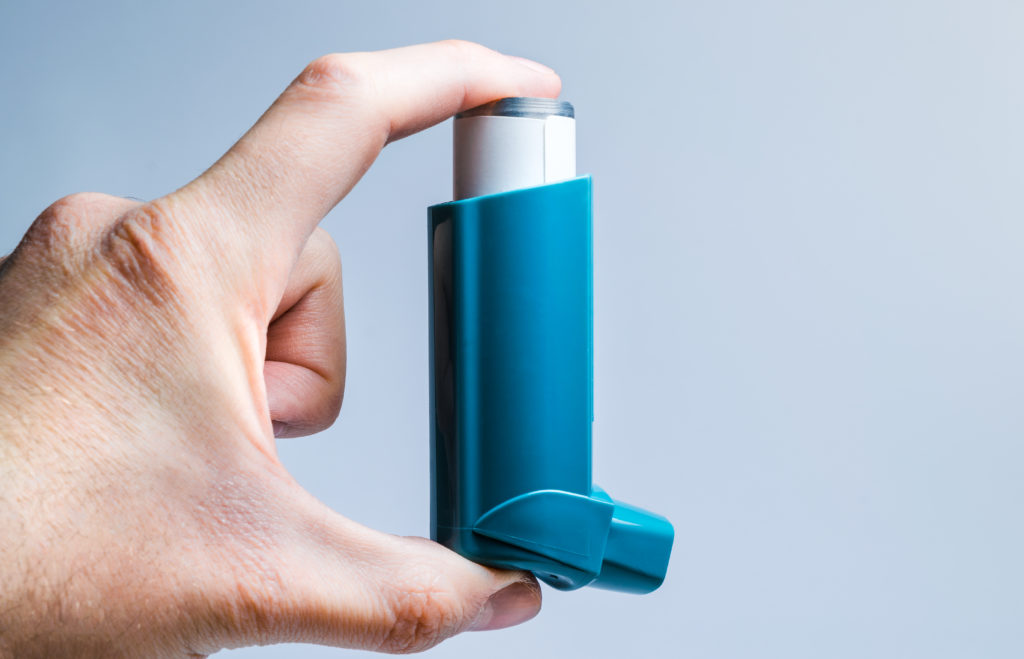 A hand holds a medical inhaler for asthma and lung diseases
