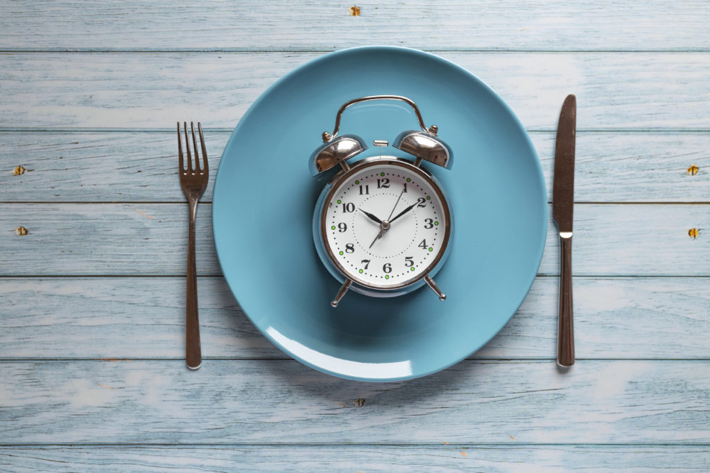 Meal planning for diet concept , Intermittent fasting concept with clock on plate, fork and knife on wooden table, Clock on plate with fork and knife, intermittent fasting, meal plan, weight loss